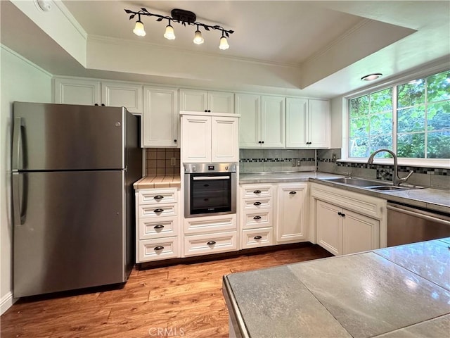 2817 San Verbena Way, Chico, CA 95973 - kitchen with stainless steel appliances, crown molding, light wood-style flooring, tasteful backsplash, and white cabinetry
