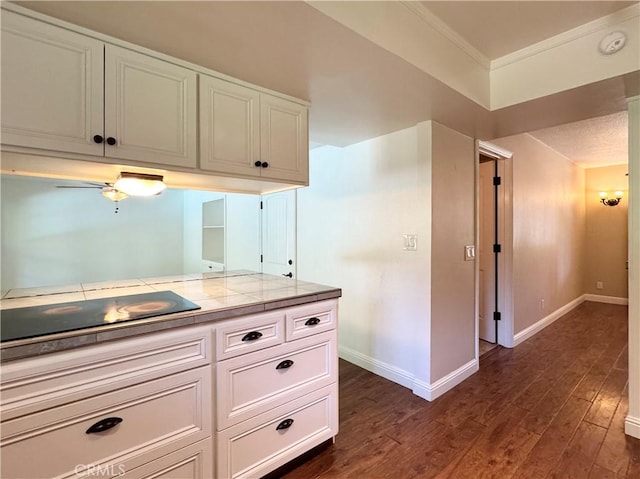 2817 San Verbena Way, Chico, CA 95973 - kitchen featuring black electric stovetop, dark wood-style floors, white cabinetry, tile countertops, and crown molding