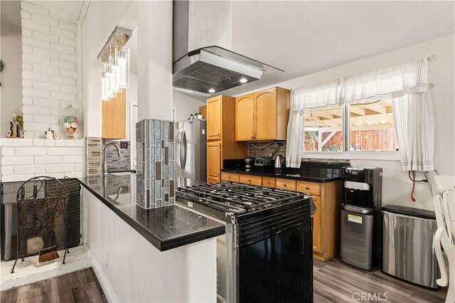 26920 14th St, Highland, CA 92346 - kitchen with range with gas stovetop, wall chimney exhaust hood, freestanding refrigerator, a peninsula, and wood finished floors
