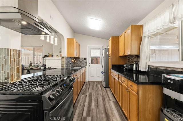 26920 14th St, Highland, CA 92346 - kitchen featuring black gas range, wall chimney range hood, vaulted ceiling, backsplash, and freestanding refrigerator