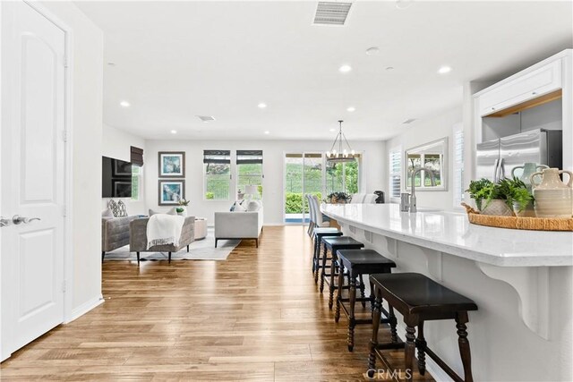 27 Cache St, Rancho Mission Viejo, CA 92694 - kitchen with freestanding refrigerator, light wood-type flooring, a breakfast bar, healthy amount of natural light, and recessed lighting