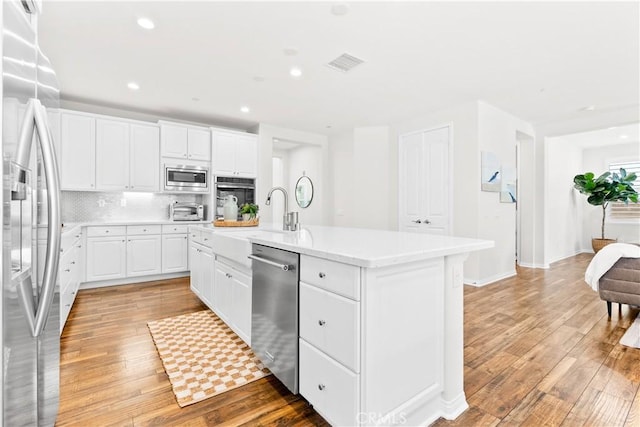 27 Cache St, Rancho Mission Viejo, CA 92694 - kitchen featuring appliances with stainless steel finishes, an island with sink, light countertops, light wood finished floors, and recessed lighting