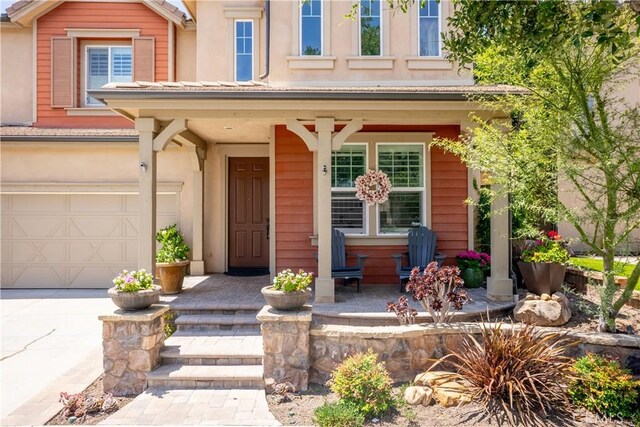 27 Cache St, Rancho Mission Viejo, CA 92694 - entrance to property with a porch, an attached garage, driveway, and stucco siding