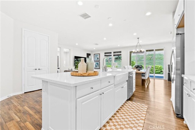 27 Cache St, Rancho Mission Viejo, CA 92694 - kitchen with light wood-type flooring, stainless steel appliances, white cabinetry, recessed lighting, and a kitchen island with sink