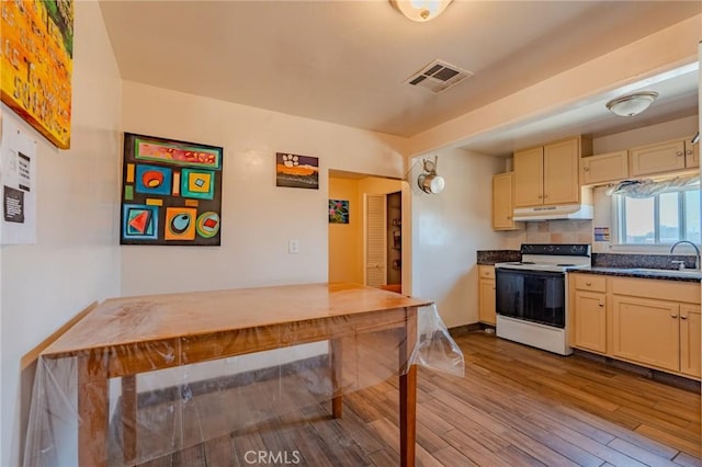 9668 W Rosamond Blvd, Rosamond, CA 93560 - kitchen featuring range with electric cooktop, under cabinet range hood, wood finished floors, cream cabinetry, and dark countertops