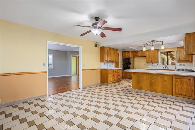 1835 Hilltop Dr, Colton, CA 92324 - kitchen with black appliances, tile countertops, a peninsula, brown cabinets, and ceiling fan