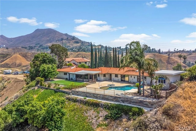 1835 Hilltop Dr, Colton, CA 92324 - rear view of house featuring a patio area, a fenced backyard, a mountain view, and an outdoor pool