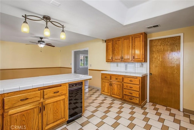 1835 Hilltop Dr, Colton, CA 92324 - kitchen with a ceiling fan, light flooring, brown cabinets, tasteful backsplash, and decorative light fixtures