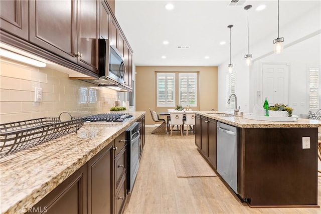 152 Jaripol Cir, Rancho Mission Viejo, CA 92694 - kitchen with appliances with stainless steel finishes, dark brown cabinetry, light wood finished floors, backsplash, and recessed lighting
