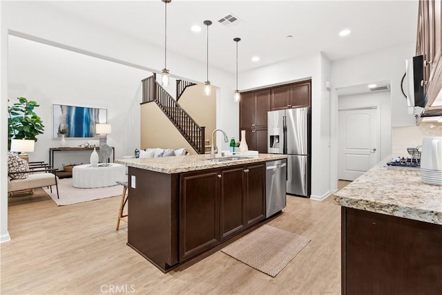 152 Jaripol Cir, Rancho Mission Viejo, CA 92694 - kitchen with stainless steel appliances, dark brown cabinetry, light wood-type flooring, open floor plan, and decorative light fixtures