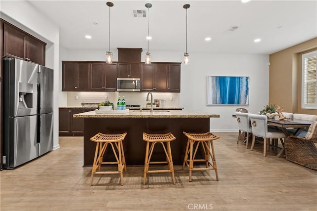 152 Jaripol Cir, Rancho Mission Viejo, CA 92694 - kitchen with appliances with stainless steel finishes, dark brown cabinetry, a kitchen breakfast bar, and recessed lighting