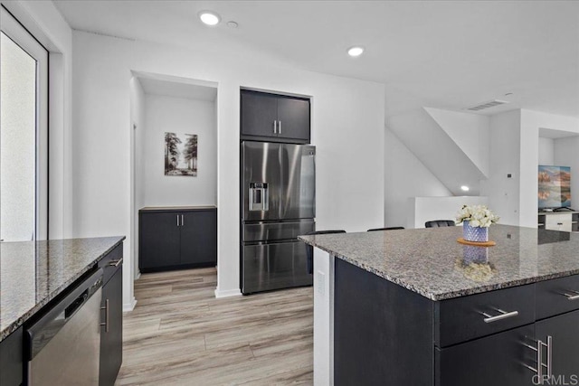 5265 Beachfront Cove St Unit 167, San Diego, CA 92154 - kitchen with appliances with stainless steel finishes, light wood-type flooring, dark stone countertops, recessed lighting, and dark cabinetry