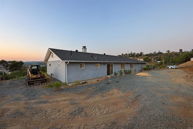 2814 Helix St, Spring Valley, CA 91977 - back of house at dusk featuring stucco siding, roof with shingles, and a chimney