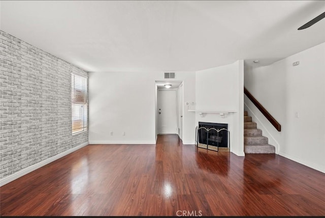 20821 E Calora St Unit E1, Covina, CA 91724 - unfurnished living room featuring brick wall, a fireplace, stairs, wood finished floors, and a ceiling fan