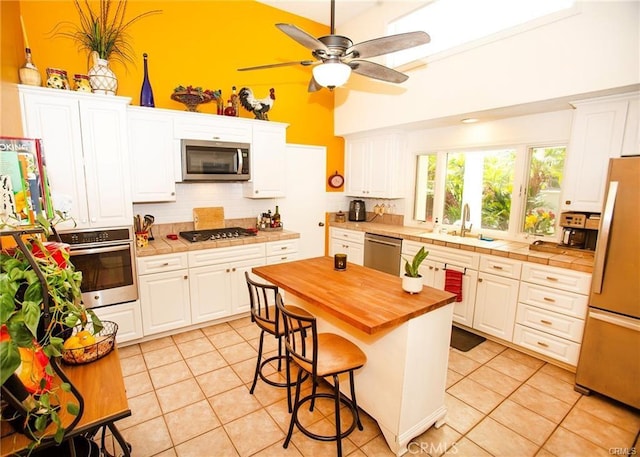 22541 Lake Forest Ln, Lake Forest, CA 92630 - kitchen featuring appliances with stainless steel finishes, tasteful backsplash, wood counters, light tile patterned flooring, and a ceiling fan
