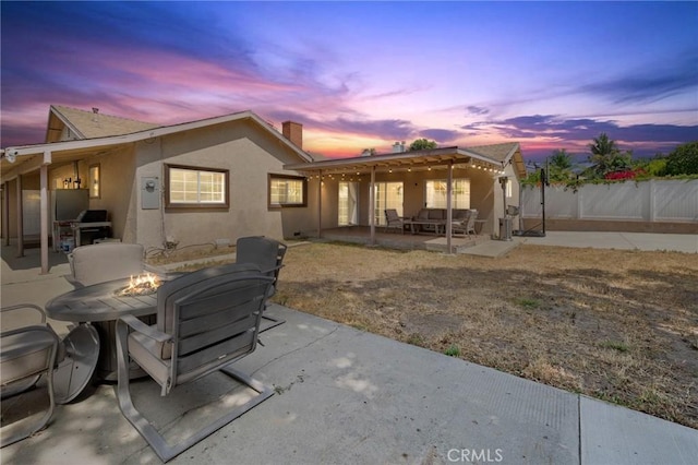 11440 Gothic Ave, Granada Hills, CA 91344 - back of house at dusk featuring an outdoor fire pit, a patio area, stucco siding, and a chimney