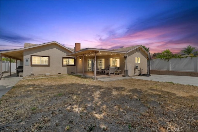 11440 Gothic Ave, Granada Hills, CA 91344 - back of property at dusk with stucco siding, a fenced backyard, and a chimney