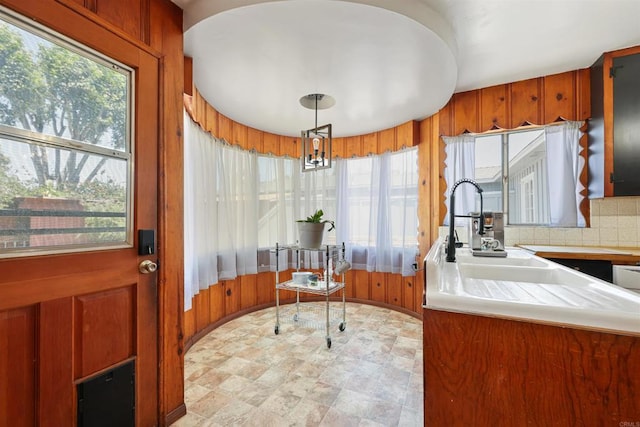 8802 Tyler St, Spring Valley, CA 91977 - kitchen featuring brown cabinets, light countertops, decorative light fixtures, wood walls, and tasteful backsplash