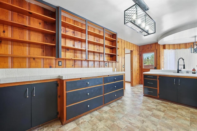 8802 Tyler St, Spring Valley, CA 91977 - kitchen featuring open shelves, stone finish flooring, light countertops, wooden walls, and a chandelier