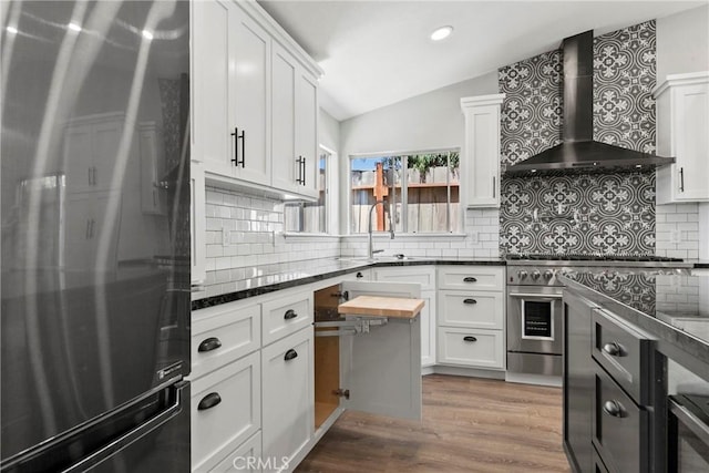 662 January St, Nipomo, CA 93444 - kitchen with appliances with stainless steel finishes, wall chimney exhaust hood, vaulted ceiling, backsplash, and wood finished floors