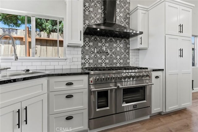 662 January St, Nipomo, CA 93444 - kitchen featuring wall chimney exhaust hood, range with two ovens, tasteful backsplash, and white cabinets