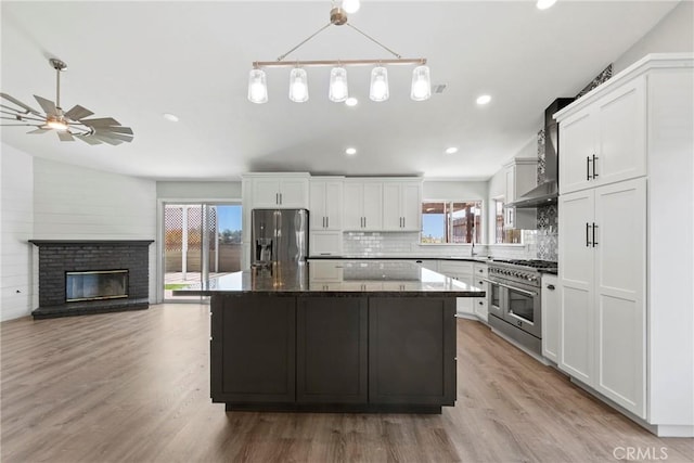 662 January St, Nipomo, CA 93444 - kitchen with appliances with stainless steel finishes, wall chimney range hood, backsplash, a kitchen island, and white cabinets