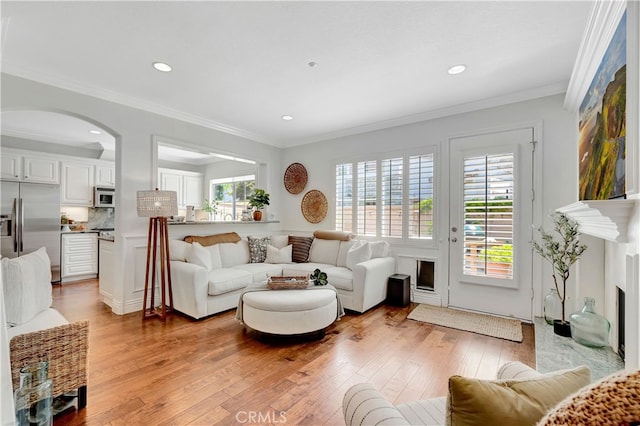6 Camino Celeste, San Clemente, CA 92673 - living room featuring light wood-style floors, arched walkways, recessed lighting, ornamental molding, and a fireplace with flush hearth