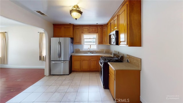 2372 W 29th Pl, Los Angeles, CA 90018 - kitchen featuring appliances with stainless steel finishes, light countertops, and brown cabinets
