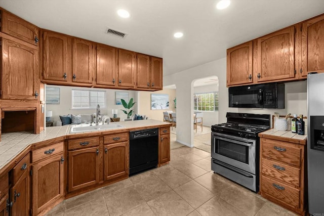 5530 Heidi St, La Mesa, CA 91942 - kitchen with black appliances, tile counters, arched walkways, brown cabinets, and recessed lighting