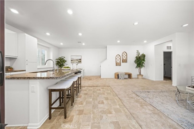 5603 Kate Way Unit 4, Fontana, CA 92336 - kitchen featuring a breakfast bar, white cabinetry, dark stone countertops, recessed lighting, and light colored carpet