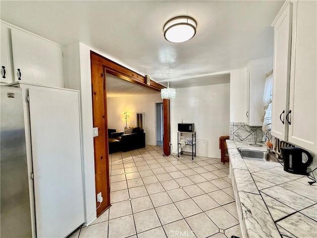 1526 Lakme Ave, Wilmington, CA 90744 - kitchen with tile countertops, white cabinets, light tile patterned flooring, stainless steel refrigerator, and decorative light fixtures