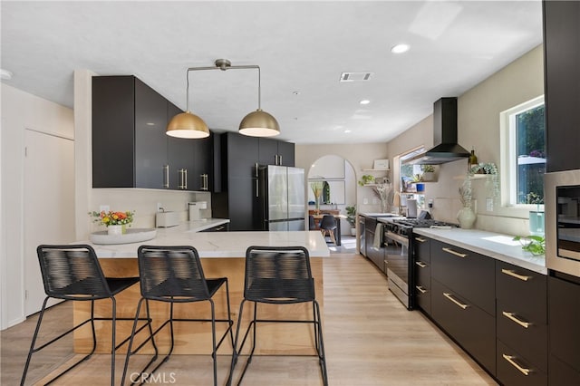 136461/2 Dronfield Ave, Sylmar, CA 91342 - kitchen featuring wall chimney range hood, stainless steel appliances, dark cabinets, a peninsula, and recessed lighting