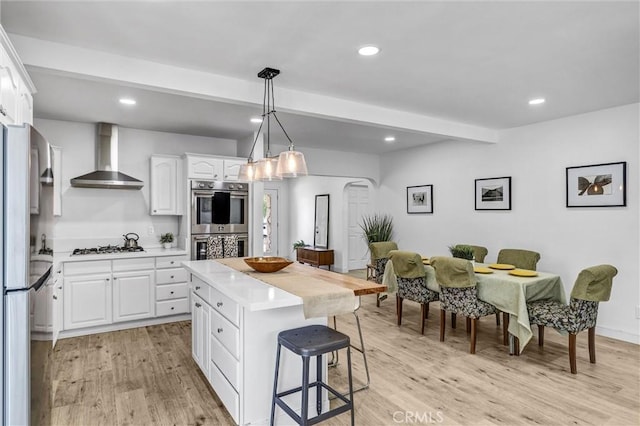 2255 Cota Ave, Long Beach, CA 90810 - kitchen with wall chimney exhaust hood, double oven, a breakfast bar, light countertops, and freestanding refrigerator