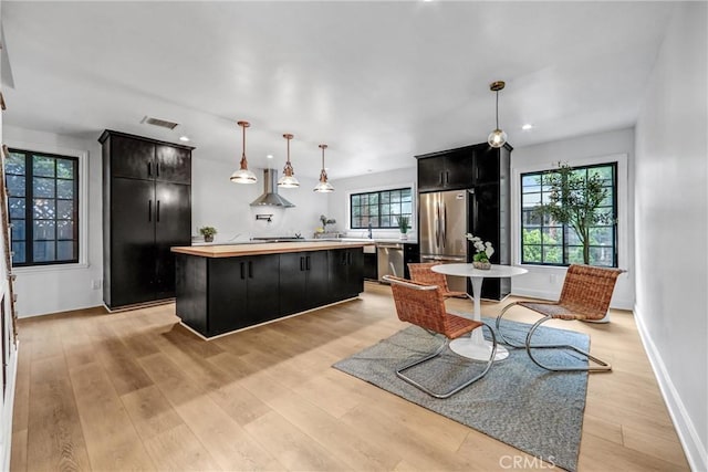 3735 Division St, Los Angeles, CA 90065 - kitchen featuring dark cabinets, wall chimney exhaust hood, a kitchen island, appliances with stainless steel finishes, and light wood-style floors
