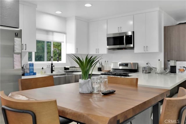 5226 W 20th St, Los Angeles, CA 90016 - kitchen with stainless steel appliances, a peninsula, recessed lighting, white cabinets, and a kitchen bar