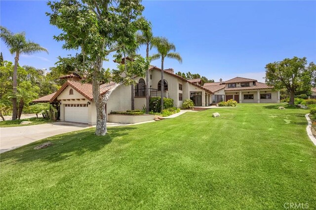 7580 E Martella Ln, Anaheim Hills, CA 92808 - mediterranean / spanish-style house featuring stucco siding, a tiled roof, a front yard, a garage, and driveway