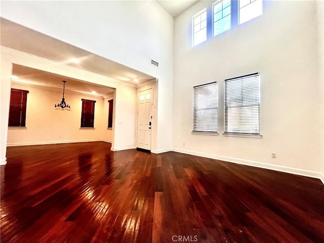 6715 Meriwether Ct, Rancho Cucamonga, CA 91701 - unfurnished living room with dark wood-type flooring, crown molding, a chandelier, and a towering ceiling