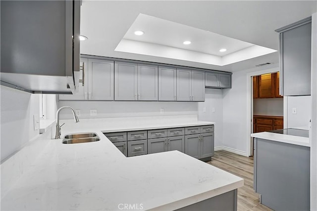 28931 Bradley Rd, Menifee, CA 92586 - kitchen with gray cabinetry, a tray ceiling, recessed lighting, light wood-style flooring, and black electric stovetop