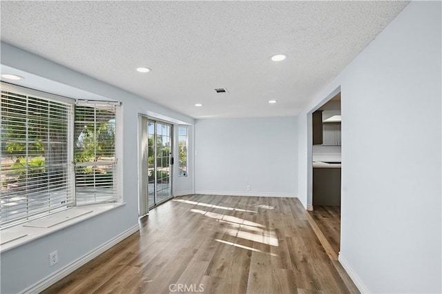 28931 Bradley Rd, Menifee, CA 92586 - unfurnished living room with wood finished floors, a textured ceiling, and recessed lighting