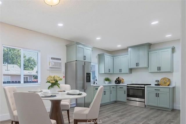 221 N Orchard St, Fresno, CA 93701 - kitchen with stainless steel gas range, fridge with ice dispenser, light wood-style floors, a wall mounted AC, and light countertops