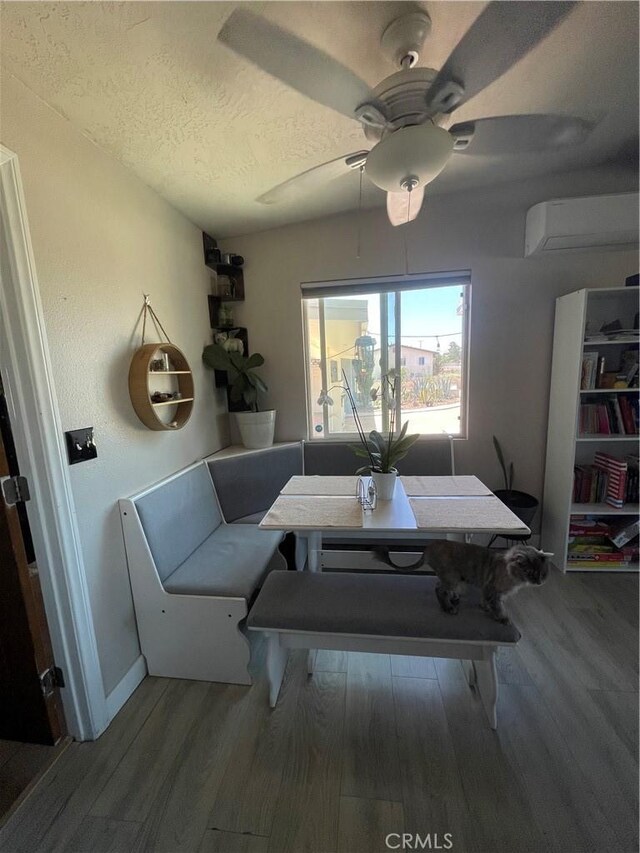 10623 4th Ave, Hesperia, CA 92345 - dining space featuring a wall unit AC, wood finished floors, a textured ceiling, and ceiling fan