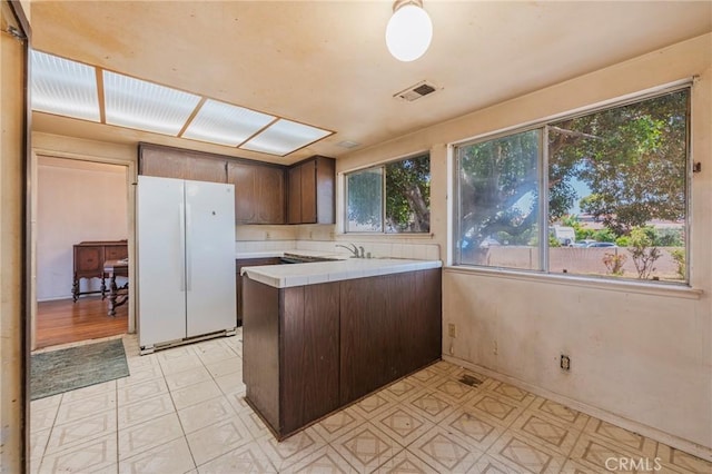 17300 Buttonwood St, Fountain Valley, CA 92708 - kitchen with freestanding refrigerator, tile counters, a peninsula, dark brown cabinetry, and light floors