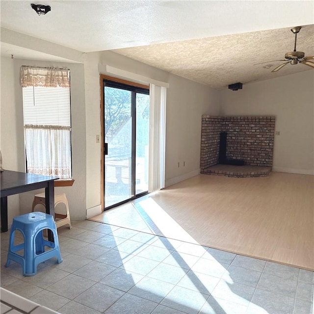 9078 Smith Rd, Phelan, CA 92371 - unfurnished living room with a textured ceiling, tile patterned floors, a fireplace, and ceiling fan