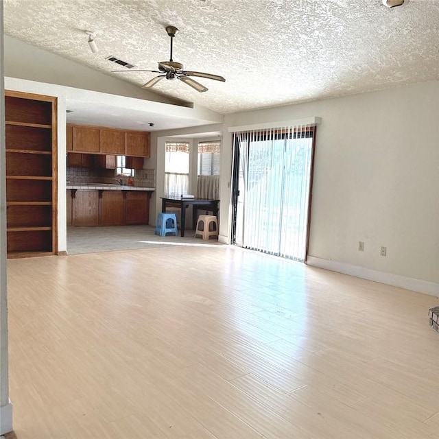 9078 Smith Rd, Phelan, CA 92371 - unfurnished living room with a ceiling fan, a textured ceiling, light wood-style flooring, and vaulted ceiling