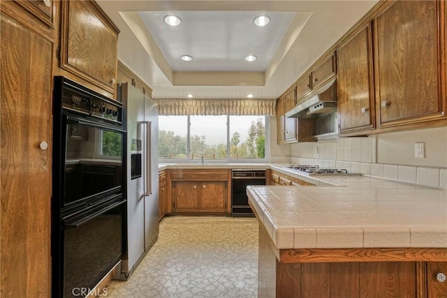 19291 Berclair Ln, Tarzana, CA 91356 - kitchen featuring black appliances, under cabinet range hood, a tray ceiling, a peninsula, and brown cabinets