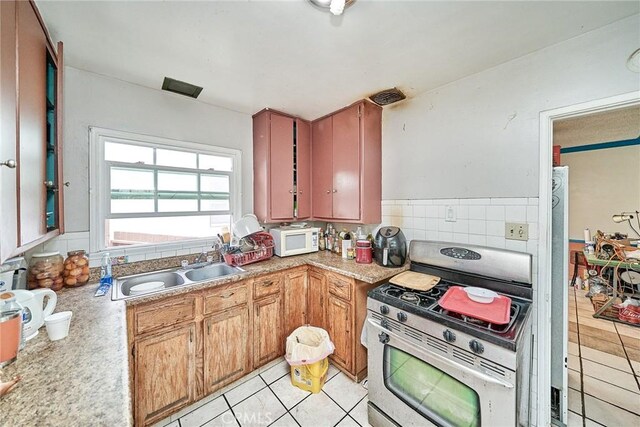 3744 Myrtle Ave, Long Beach, CA 90807 - kitchen with gas range, white microwave, light tile patterned floors, and light countertops