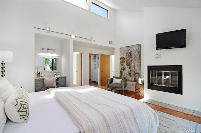 828 Wonder View Dr, Calabasas, CA 91302 - bedroom with a towering ceiling, multiple windows, wood finished floors, and a glass covered fireplace