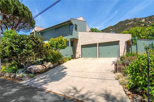 828 Wonder View Dr, Calabasas, CA 91302 - view of front of property featuring concrete driveway, a garage, a mountain view, and stucco siding