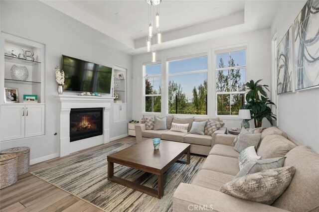 11 Juniper, Lake Forest, CA 92630 - living area featuring a tray ceiling, wood finished floors, healthy amount of natural light, and a glass covered fireplace
