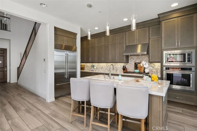 11 Juniper, Lake Forest, CA 92630 - kitchen featuring built in appliances, under cabinet range hood, recessed lighting, decorative backsplash, and light countertops